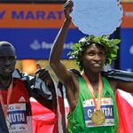 Geoffrey Mutai, who set a new course record, hold his plate with second place finisher Emmanuel Mutai (no relation) on the left
